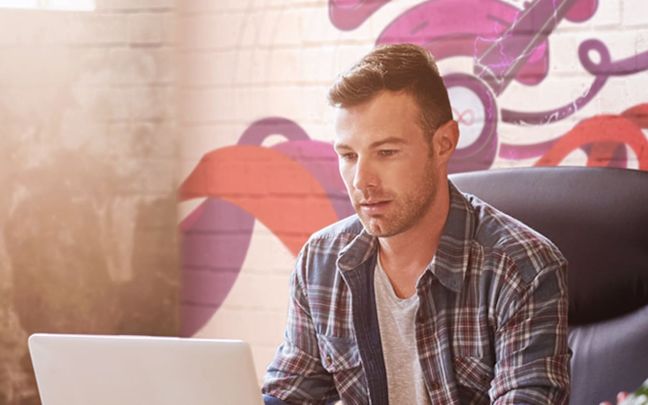 A remote worker sits at his desk with his laptop