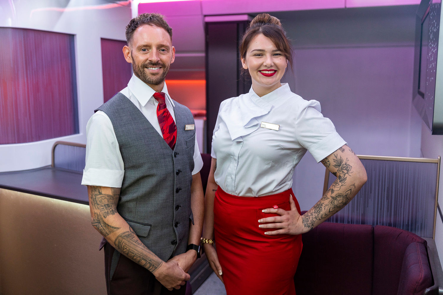 Two members of Virgin Atlantic crew showing off their tattoos