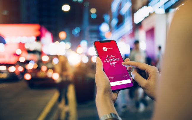 A person holding a phone showing the Virgin Money Australia app