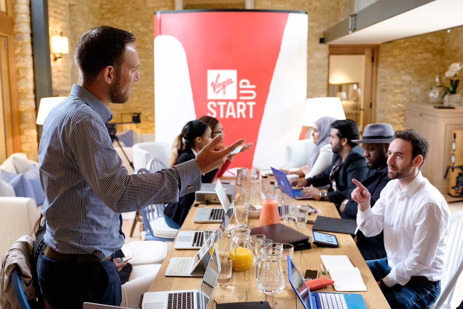 A group of Virgin StartUp founders in a meeting around a long table