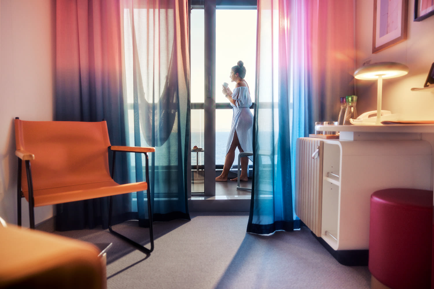 A woman standing on the balcony of a Virgin Voyages cabin