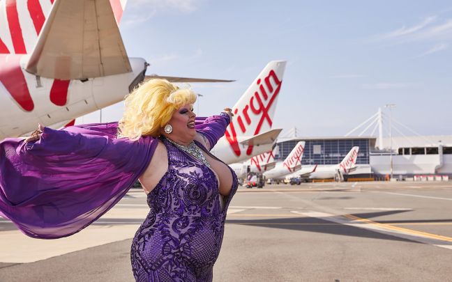 A drag queen posing next to Virgin Australia aircraft