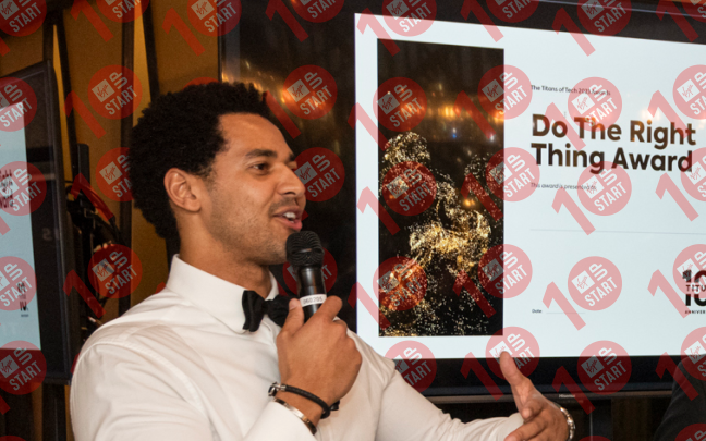 Seb Francis, co-founder of Titus Learning, speaking into a microphone. A screen in the background reads "Do The Right Thing Award"