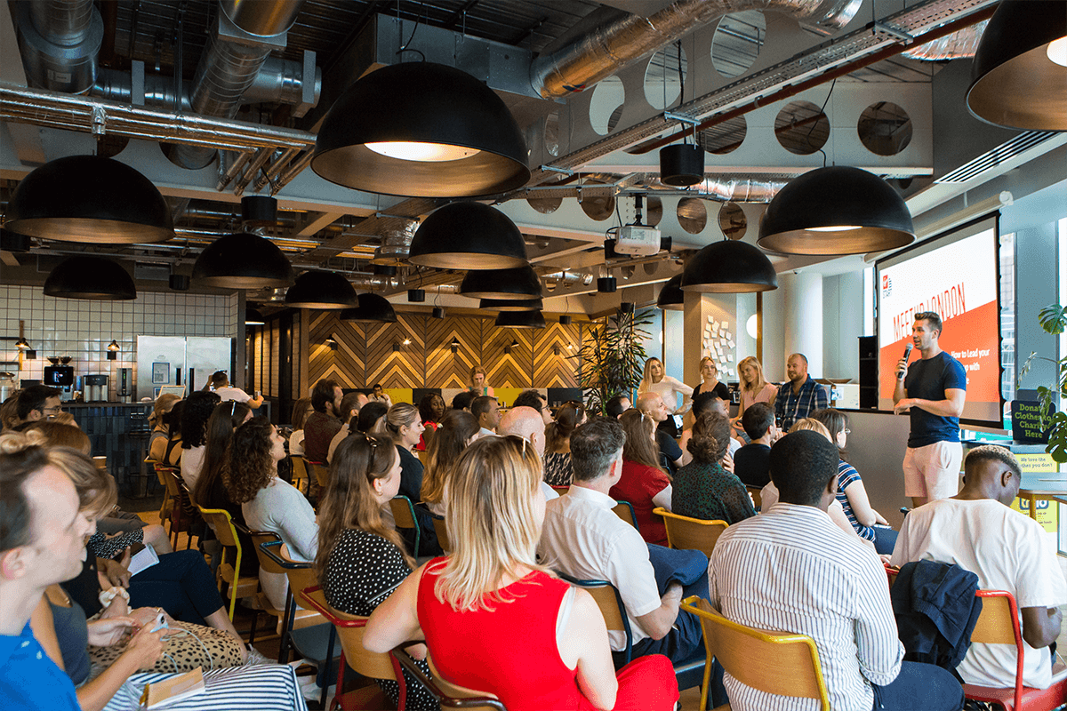 A room full of people sit listening to a presentation about Virgin Start up